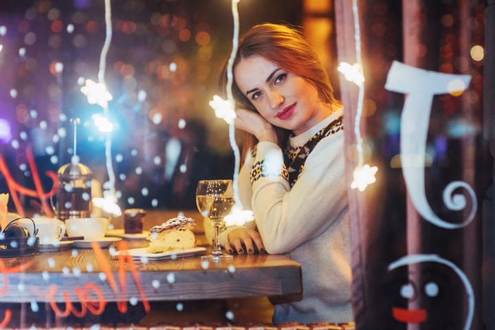 Young beautiful woman sitting in cafe, drinking wine. Christmas, new year, Valentines day, winter holidays concept