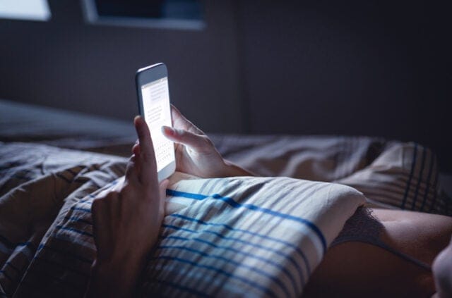 woman's hands texting in dark room