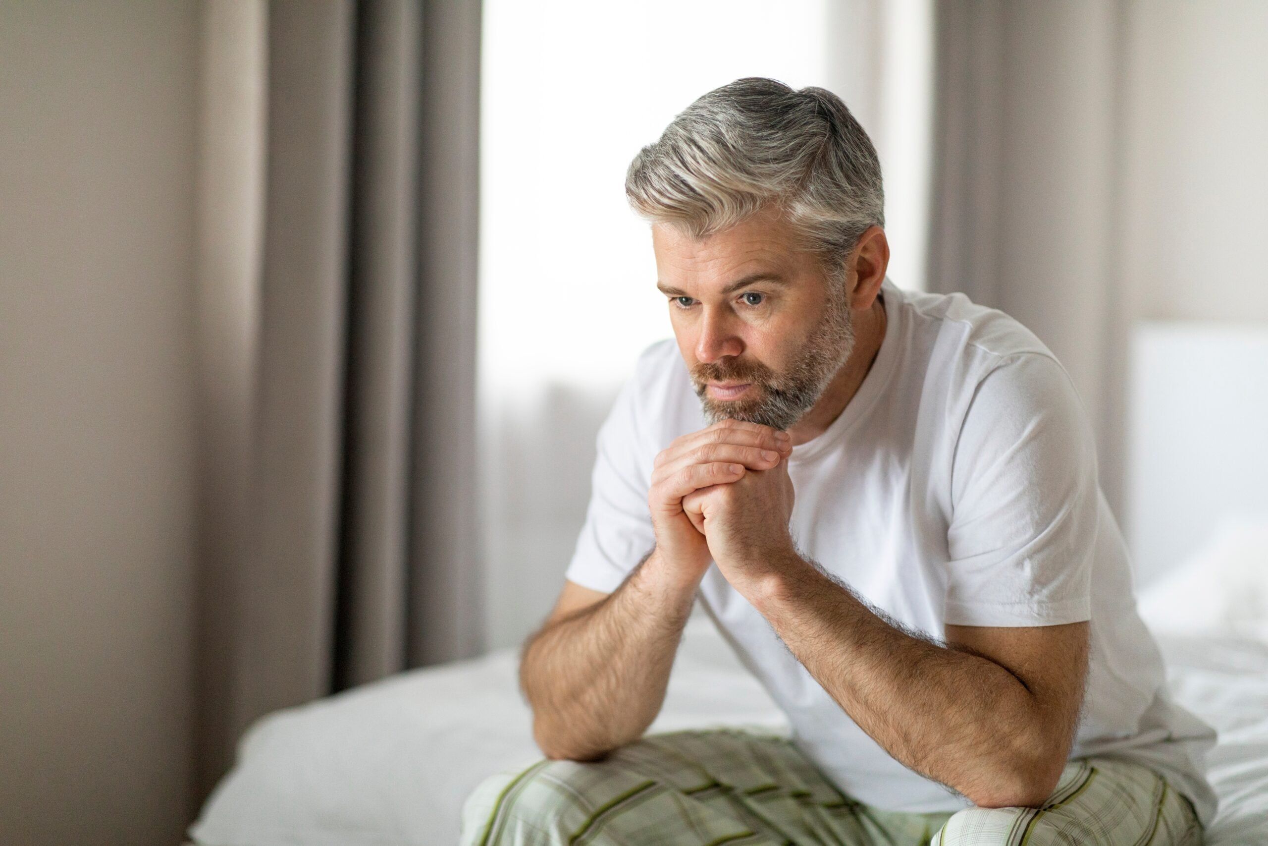 A middle aged man sitting alone thinking about his life.