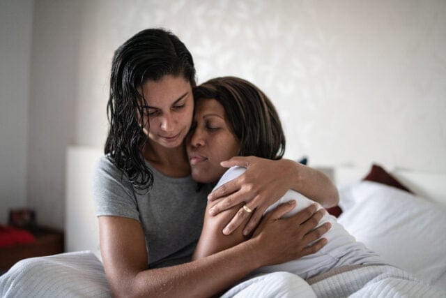 lesbian couple hugging in bed