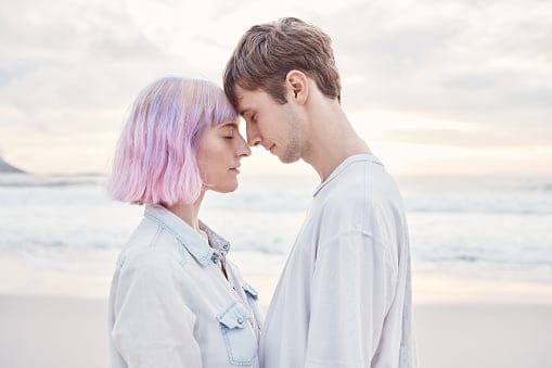 A young couple in love, at the beach with their foreheads touching