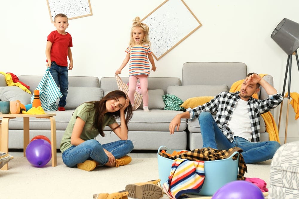 Frustrated parents and their mischievous children in their messy room