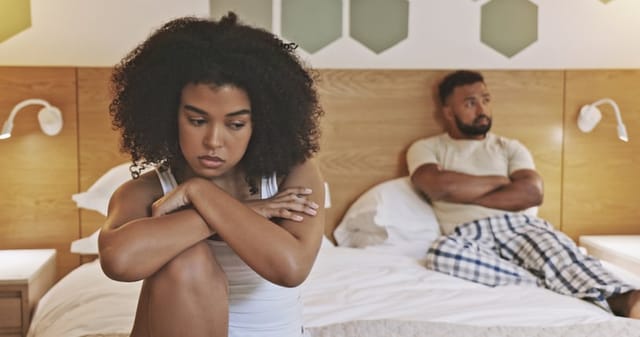 sad woman on edge of bed with boyfriend