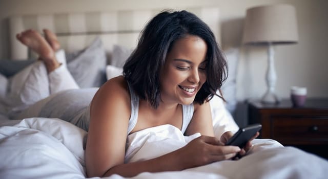 smiling woman texting in bed