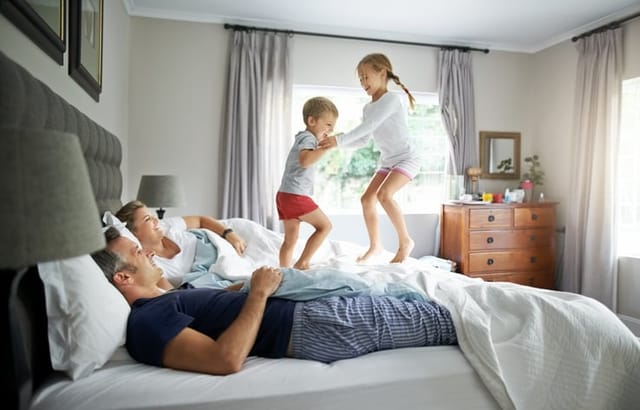 couple in bed with kids jumping