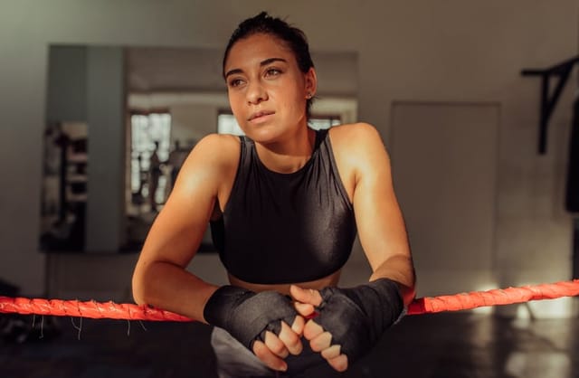 thoughtful female boxer leaning on ring