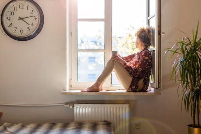 woman sitting on window seat looking out