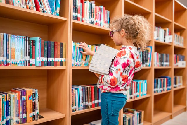 little girl gathering library books