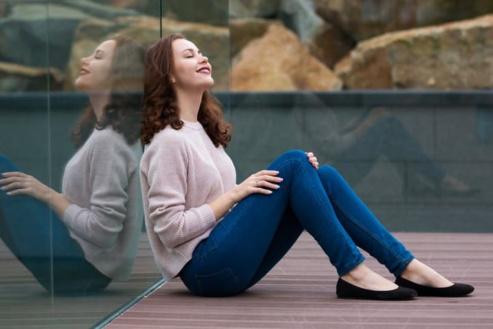 Reflection of beautiful cute fashionable girl in modern glass building