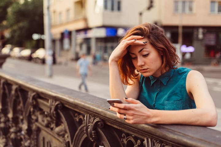 young woman upset texting outdoors