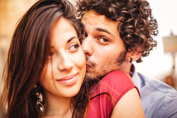 man kissing woman's cheek